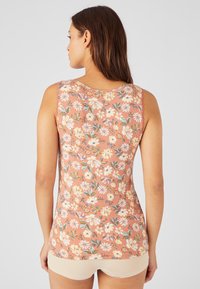 Top floreale senza maniche di colore rosa salmone, con scollo rotondo. Il motivo include piccoli fiori bianchi, gialli e verdi.