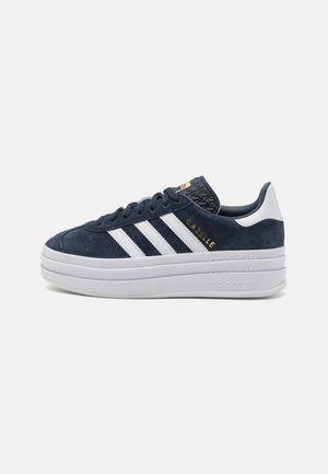 Sneaker Adidas Gazelle blu navy con strisce bianche, logo dorato, suola platform bianca a triplo strato e linguetta nera strutturata.