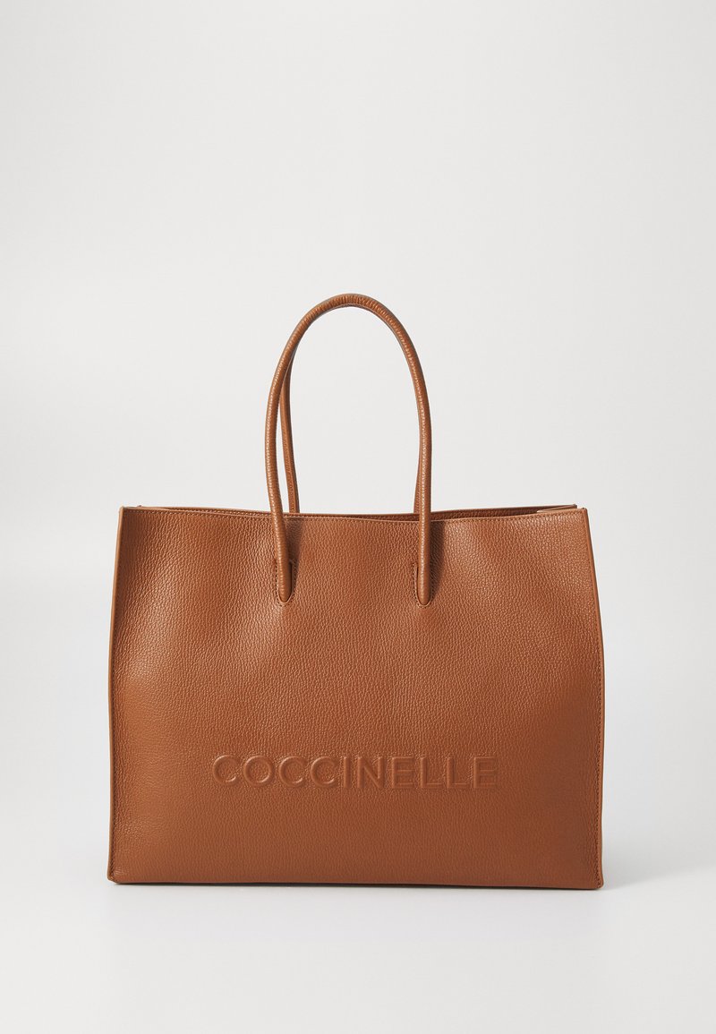 Brown leather tote bag with a textured finish, featuring two handles and embossed branding on the front. Rectangular shape.