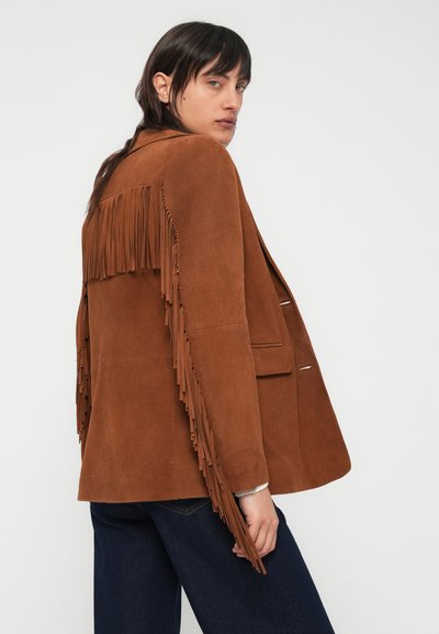 Pruun seemisnahast jakk, millel on seljal ja varrukatel tuttidega kaunistus, kujundatud istuvaks ning kahe ees oleva taskuga.