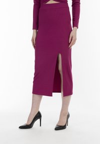 Figurbetontem magentafarbenes Ripprock mit einem Schlitz vorne. Kombiniert mit schwarzen spitzen High Heels. Weiche Textur und enganliegendes Design.