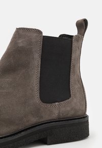 Szare zamszowe botki za kostkę z czarnym elastycznym panelem bocznym, przeszyciami oraz fakturowaną czarną gumową podeszwą.