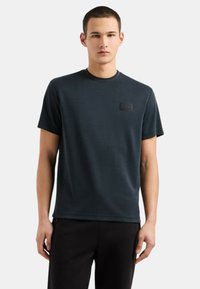 T-shirt a maniche corte blu scuro realizzato in tessuto morbido, con colletto rotondo e un'etichetta logo testurizzata sul petto.