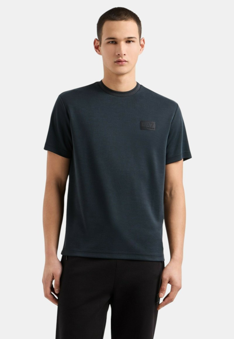 T-shirt a maniche corte blu scuro realizzato in tessuto morbido, con colletto rotondo e un'etichetta logo testurizzata sul petto.