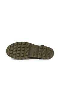 Semelle d'une chaussure avec un design robuste, en caoutchouc. Elle possède des crampons épais pour une meilleure adhérence et est principalement de couleur vert olive.