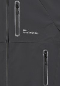 Graue Jacke mit zwei Reißverschlusstaschen mit klaren Kanten, "HALO"-Text und Zahlen, die auf dem Brustbereich gestickt sind. Glatte Textur und minimalistisches Design.
