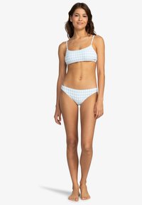 Conjunto de bikini azul claro con un patrón de pata de gallo. La parte superior tiene tirantes finos, y la parte inferior es de corte clásico con bordes suaves.