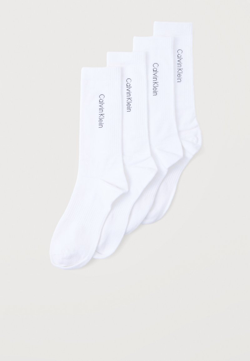 Τέσσερα ζεύγη λευκές κάλτσες τύπου μέσης, στοιβαγμένες, η κάθε μία με μαύρο λογότυπο "Calvin Klein" στη πλευρική μανσέτα, πάνω σε απλό ανοιχτό φόντο.