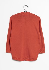 Rostfärgad stickad tröja med rund halsringning, långa ärmar samt ribbade mudd och nederkant, hängande på en svart krok mot en vit bakgrund.