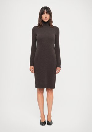 Turtleneck dress in dark brown knit, fitted shape, long sleeves, ribbed cuffs and hem, knee-length, paired with black shoes.