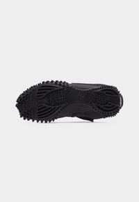 Μαύρη αθλητική σόλα παπουτσιού με υφή λαβής που διαθέτει καρφιά και αυλακώσεις για πρόσφυση, εμφανιζόμενη από κάτω σε λευκό φόντο.