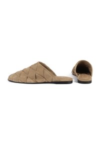 Las mules de ante beige sin hebilla presentan un diseño acolchado con patrones triangulares, suela plana negra y parte trasera abierta para un uso fácil.