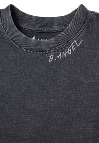 Camiseta de algodón gris oscuro con cuello redondo acanalado y un estampado en estilo manuscrito "B.ANGEL" en el lado izquierdo. Textura suave en general.