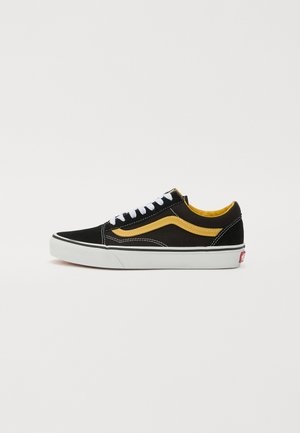 Mustmust ja kollane sametist sneaker, valgete paeltega, kontrastse kollase külgtriibuga, valge vaheosa ja punase logoga kanna kohal.