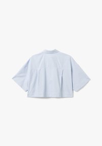 Camicetta accorciata azzurro chiaro con strisce verticali bianche, colletto e maniche corte. Le pieghe sul retro aggiungono un tocco di dettaglio al design rilassato.