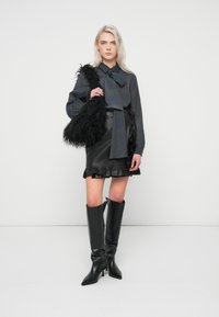 Raibā krekla ar loku, ādas mini svārki ar viļņotu apakšmalu, melni augstpapēžu zābaki līdz ceļgaliem un pūkaina melna rokassoma.