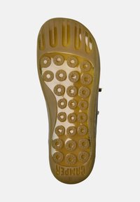 Transparent rubber sole with circular textured grip points, featuring a gold-brown color and brand logo. Size 38 indicated.
