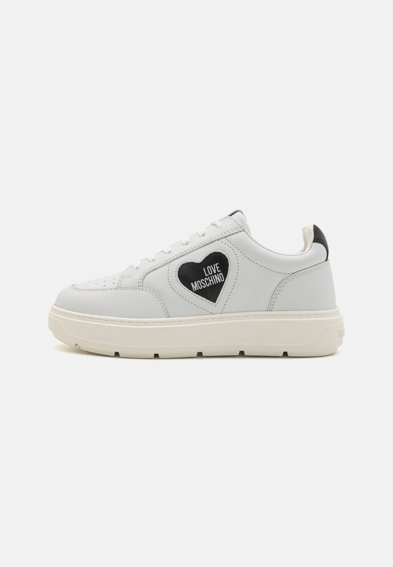 White leather sneakers with a heart-shaped black patch featuring "LOVE MOSCHINO" text. Thick cream-colored sole, round toe, and black accents.