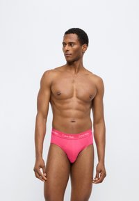 Ροζ βαμβακερά εσώρουχα με φαρδύ ελαστικό ζωνάρι που φέρει το λογότυπο «Calvin Klein» σε ανοιχτό ροζ. Λείο υφή, εφαρμοστό σχέδιο και ψηλές ανοίγματα στα πόδια.