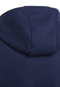 Primo piano di tessuto blu navy che mostra il bordo piegato e cucito di un cappuccio su un indumento.