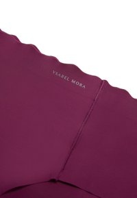 Prenda burdeos sin costuras con bordes festoneados, que presenta una textura suave y una etiqueta que dice "Ysabel Mora" en plateado.