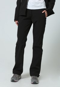 Pantalones negros elásticos de corte ajustado. Cuentan con una textura suave, detalles de costura sutil y un bolsillo en la parte delantera. Adecuados para ropa activa.