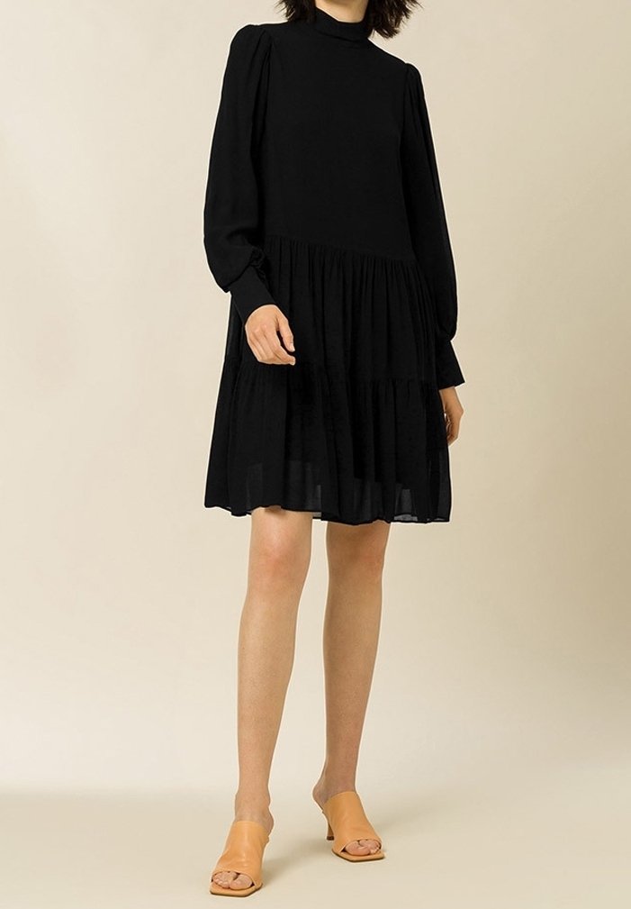 Musta pitkähiha dressi korkealla kaula-aukolla, kerroksitettu hameosa ja pehmeä tunne. Yhdistetty vaaleanruskeisiin liukuhihnakenkiin.