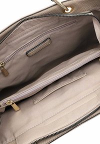 Beige håndtaske indvendig med en glat tekstur. Har to lynlåslommer, en slip-lomme og hardware aksenter i guldfarve.