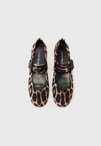 Chaussures Mary Jane en imprimé léopard, fabriquées en tissu doux, avec un bout rond, une boucle centrale et des accents noirs sur la semelle.