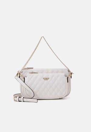 Sac à main matelassé en cuir blanc Guess avec bandoulière chaîne dorée, poche zippée avant et bandoulière en cuir ajustable et amovible.