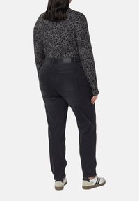 Czarne dżinsy z wysokim stanem o dopasowanym kroju, wykonane z denimu. Połączone z szarą bluzką z długim rękawem w panterkę i casualowym obuwiem.