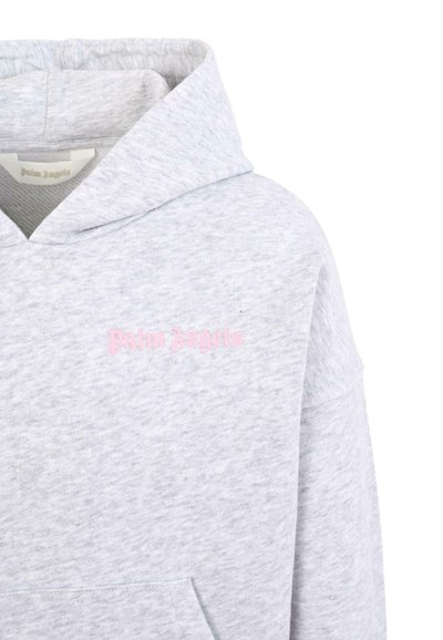 Felpa grigia con cappuccio realizzata in morbido tessuto, con una tasca e un logo rosa "Palm Angels" sul davanti. La texture è liscia e felpata.