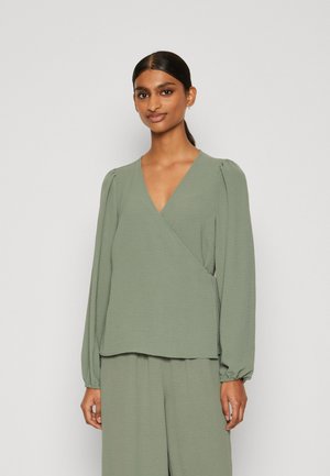 Long-sleeve, wrap-style blouse in soft, textured sage green fabric. Features a V-neckline and slightly puffed sleeves for a relaxed fit.