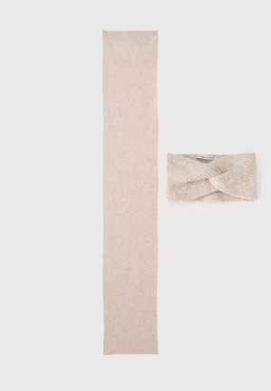 Écharpe beige en tricot à côté d'un bandeau beige assorti en tricot avec un motif torsadé sur fond blanc.