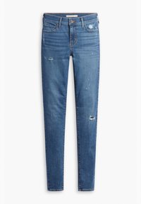 Jeans ajustados en denim azul claro con detalles desgastados, zonas desvaídas y costuras mínimas. Cuenta con cremallera y pasadores para cinturón.