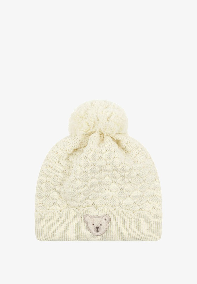 Bonnet crème tricoté avec un motif texturé, sommet arrondi et un pompon duveteux. Présente un patch de visage d'ours à l'avant.
