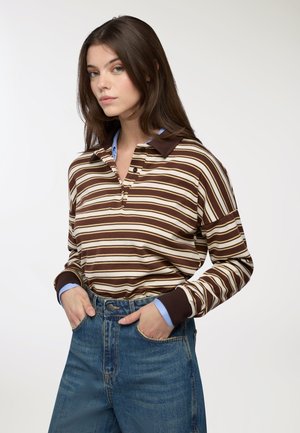 Polo a maniche lunghe a righe marroni e crema con colletto marrone e dettagli azzurri, abbinato a jeans in denim a vita alta.
