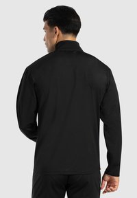 Zwarte langemouwen shirt met een kraag, gemaakt van gladde stof, met een rechte snit en zonder zichtbare patronen of versieringen.
