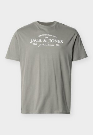 Gaiši pelēka īsroku T-krekls ar baltu tekstu "Creative Community 1990 Jack & Jones Reg. premium TM" krūšu rajonā.