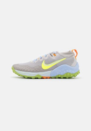 Lichtgrijze mesh sneaker met neongele Nike-swoosh, lichtblauwe tussenzool, groene buitenzool, oranje veterlussen en oranje hieltrekkoord.