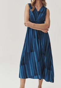 Ärmlös, blå midi-klänning med v-ringning och plisserad design. Har varierande mörka och ljusa randiga mönster samt ett elastiskt midjeband.