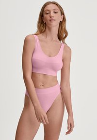 Bralette rose clair et bas de bikini taille haute assorti, fabriqués en tissu doux. Design simple et sans coutures avec des bretelles larges et une ceinture.