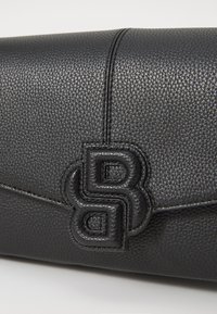 Sac en cuir noir texturé avec un logo en relief. Il a une forme rectangulaire épurée avec un détail de couture.