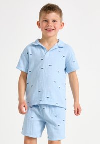 Svetle modrý dětský krátký rukáv tričko a šortky, s malými vzory lodí, texturovaná látka a uvolněný design límce.