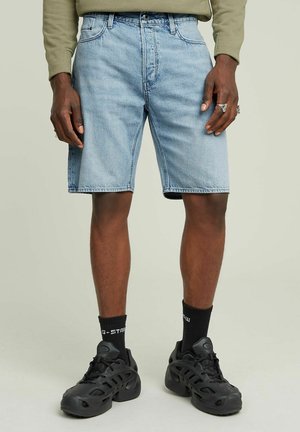 Shorts in denim bluastro con vestibilità dritta, design a cinque tasche e orlo grezzo. Indossati con sneakers nere e calzini neri a crew.