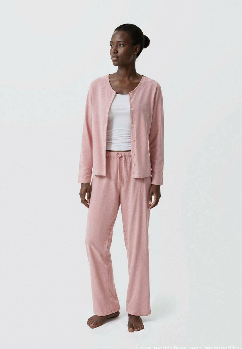 Ljust rosa pyjamasset med en knappradad topp och byxor med dragsko, tillverkat av mjukt tyg med en slät yta.