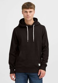 Sudadera negra con bolsillo frontal tipo canguro, capucha con cordón y puños de canalé; presenta un logo en el dobladillo y cordones blancos.