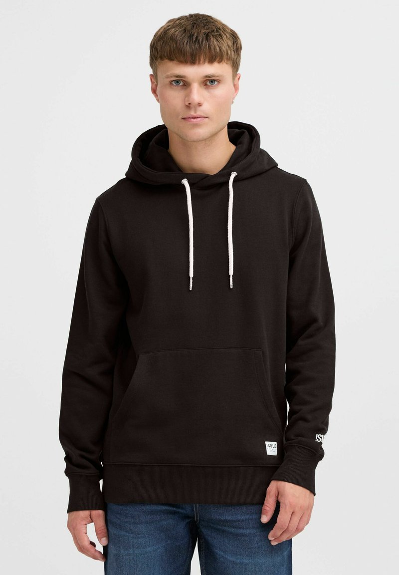 Sudadera negra con bolsillo frontal tipo canguro, capucha con cordón y puños de canalé; presenta un logo en el dobladillo y cordones blancos.