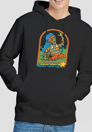 Smiling person wearing black hoodie with colorful graphic of zombie rising from grave and "Never Give Up" text beneath.