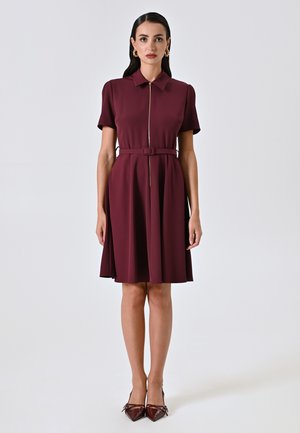 Abito bordeaux a maniche corte con colletto, zip centrale, cintura in vita e gonna svasata. Tessuto liscio, design alla lunghezza del ginocchio.